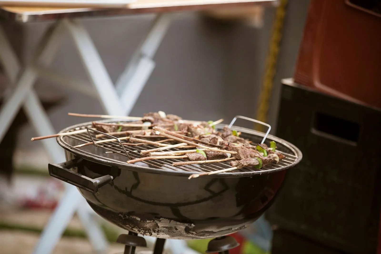Meat skewers with green pepper pieces cooking over charcoal