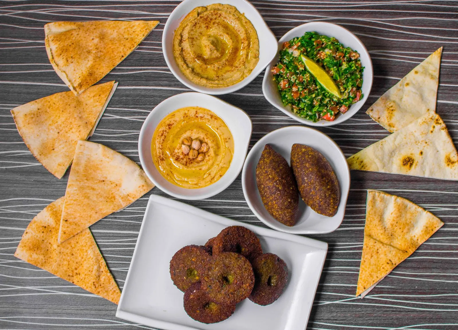 Overhead view of a mezze spread with hummus, tabbouleh, kibbeh, falafel and pita bread